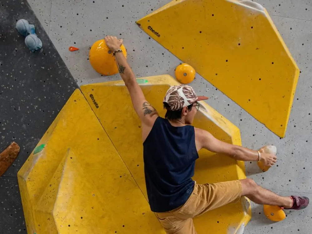 Boulderer greift an gechalkte Griffe in der Halle